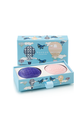 Two bath soaps, one purple and one pink, in a decorative box with airplane and hot air balloon designs on a white background.