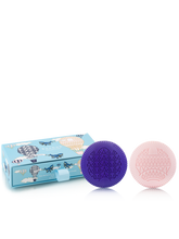 Two soaps, one purple and one pink, in front of a blue box with airplane designs on a white background.