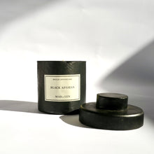 Black metal cylinder Mad et Len Candle Apothicaire Petite - Black Afghan - with lid on the side. 