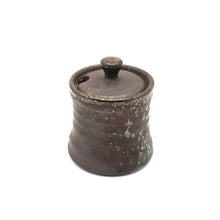 Small ceramic jar with a lid on a white background