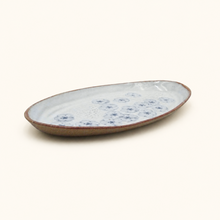 Oval ceramic plate with blue floral pattern on a white background