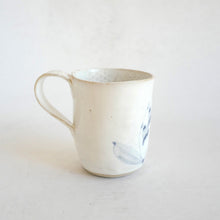 White Mug with blue flower pattern on beige background