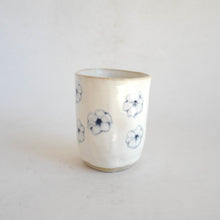 White Tumbler with blue flower pattern on beige background