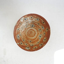 Ceramic bowl with brown and blue floral speckled design on a white background