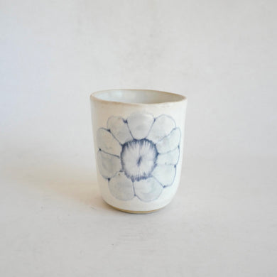 White Tumbler with blue flower pattern on beige background