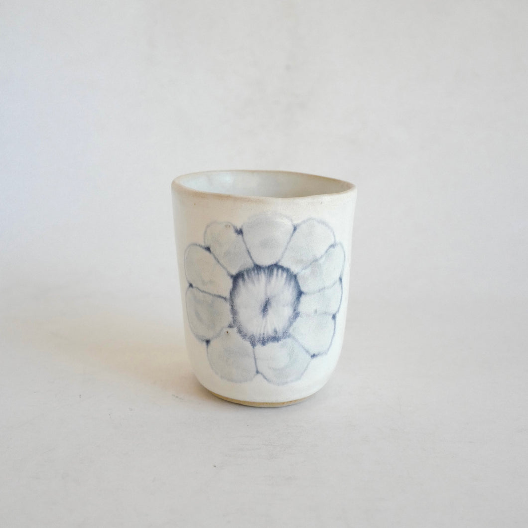 White Tumbler with blue flower pattern on beige background