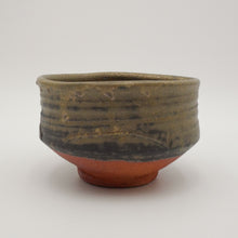 A handmade ceramic tea bowl with a textured, ribbed upper body in earthy olive-brown and dark charcoal glaze, and a contrasting terracotta orange-red glazed base, shown on a neutral light gray background.