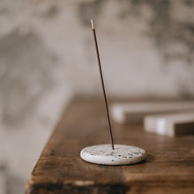 Incense stick on a ceramic holder on a wooden surface with a blurred background