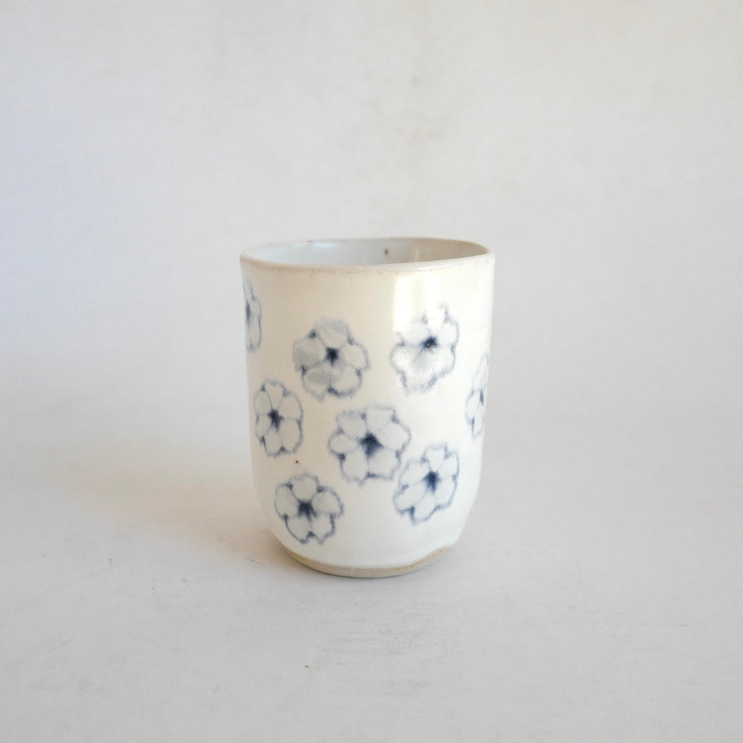 White Tumbler with blue flower pattern on beige background