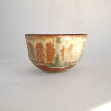Ceramic bowl with brown and green glaze on a white background