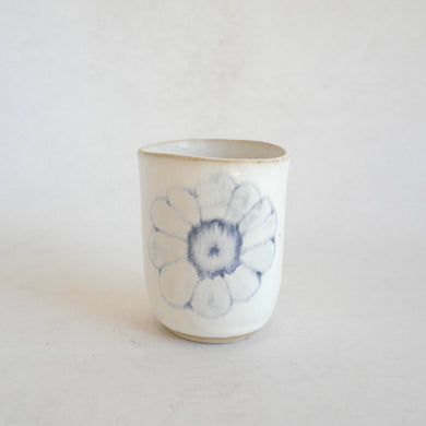 White Tumbler with blue flower pattern on beige background