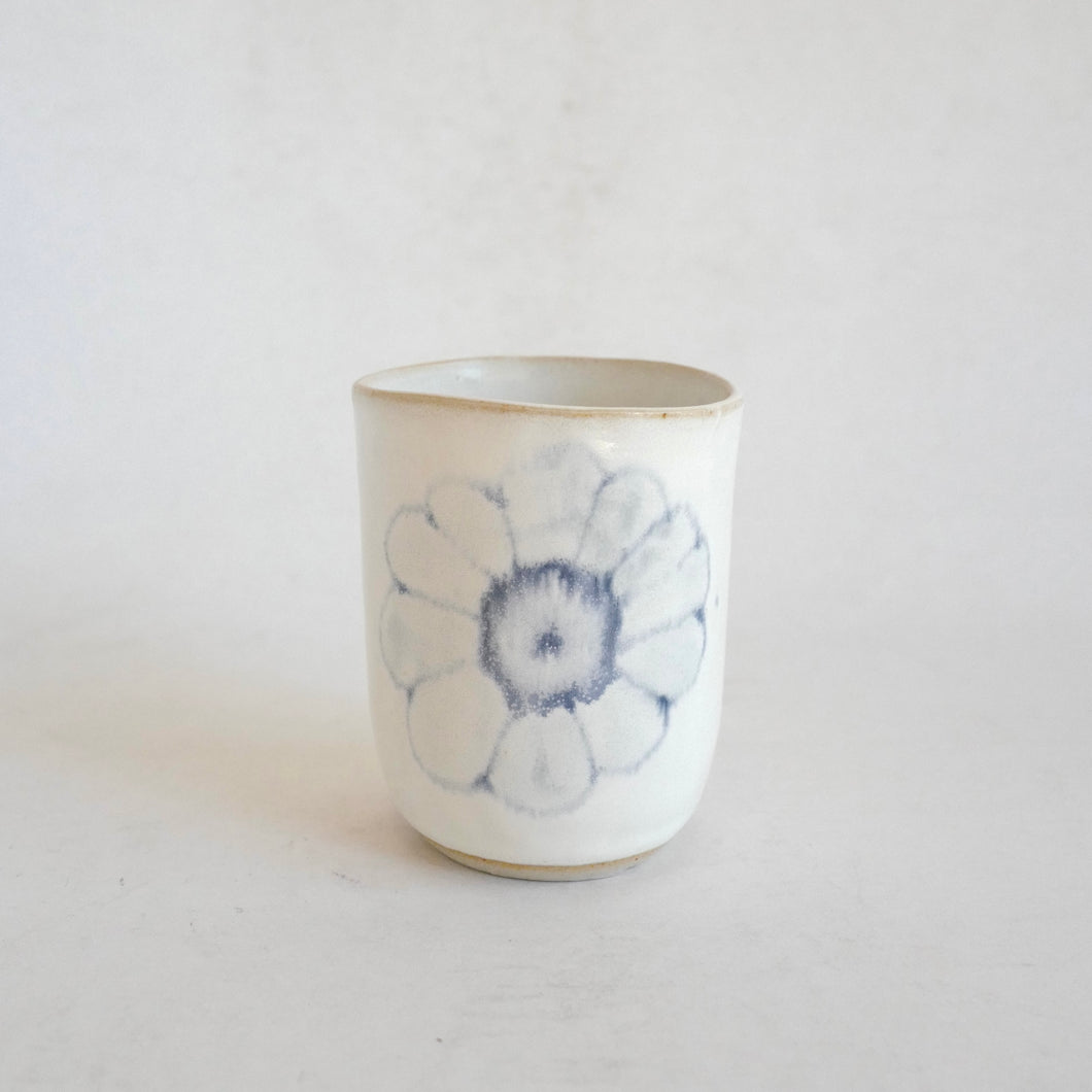 White Tumbler with blue flower pattern on beige background