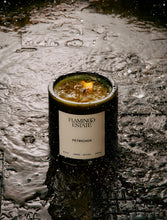 Candle labeled 'Flamingo Estate Petrichor' on a wet surface