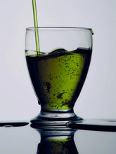 Olive oil poured into a glass on a reflective surface