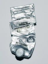 Foil tube labeled 'Jasmine Damask Rose' and 'Rich Cream' on a gray background.