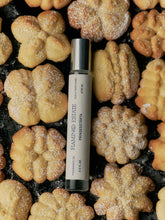 Perfume bottle labeled 'Flamingo Estate' on a background of star-shaped cookies.