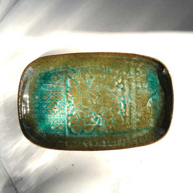 Rectangular ceramic dish with green and brown glaze on a white background
