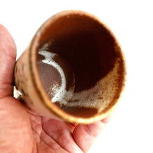 Hand holding a small ceramic cup on a white background