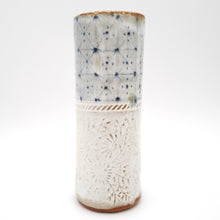 Cylindrical ceramic vase with textured surface on a white background