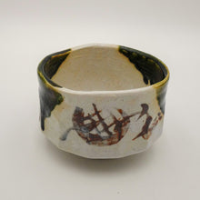 A handmade ceramic bowl with a textured, multi-toned glaze featuring dark green, brown, and off-white colors, photographed on a neutral light gray background.