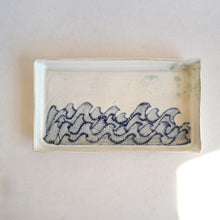 Rectangular ceramic dish with wavy pattern on a white background