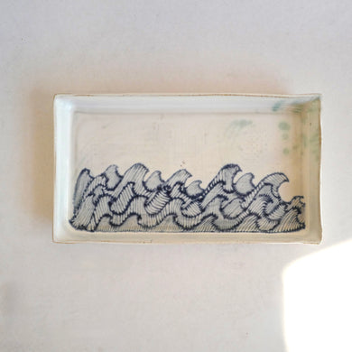 Rectangular ceramic dish with wavy pattern on a white background