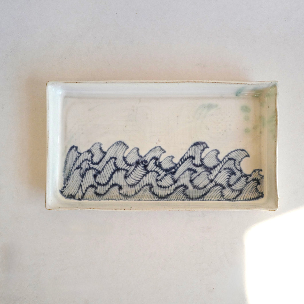 Rectangular ceramic dish with wavy pattern on a white background