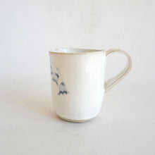 White Mug with blue flower pattern on beige background