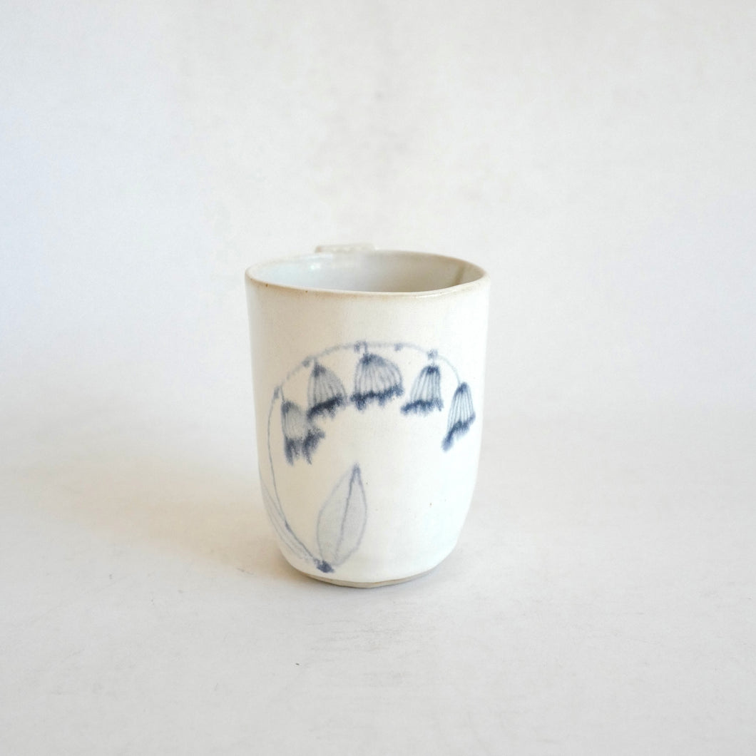 White Mug with blue flower pattern on beige background