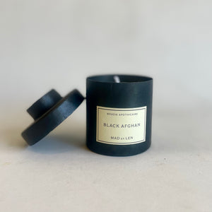 Black candle with a label on a light gray background
