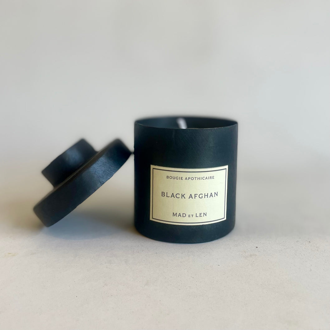 Black candle with a label on a light gray background