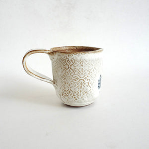 Spako Clay mug. Blue line drawing of florals and emboss pattern, white glaze