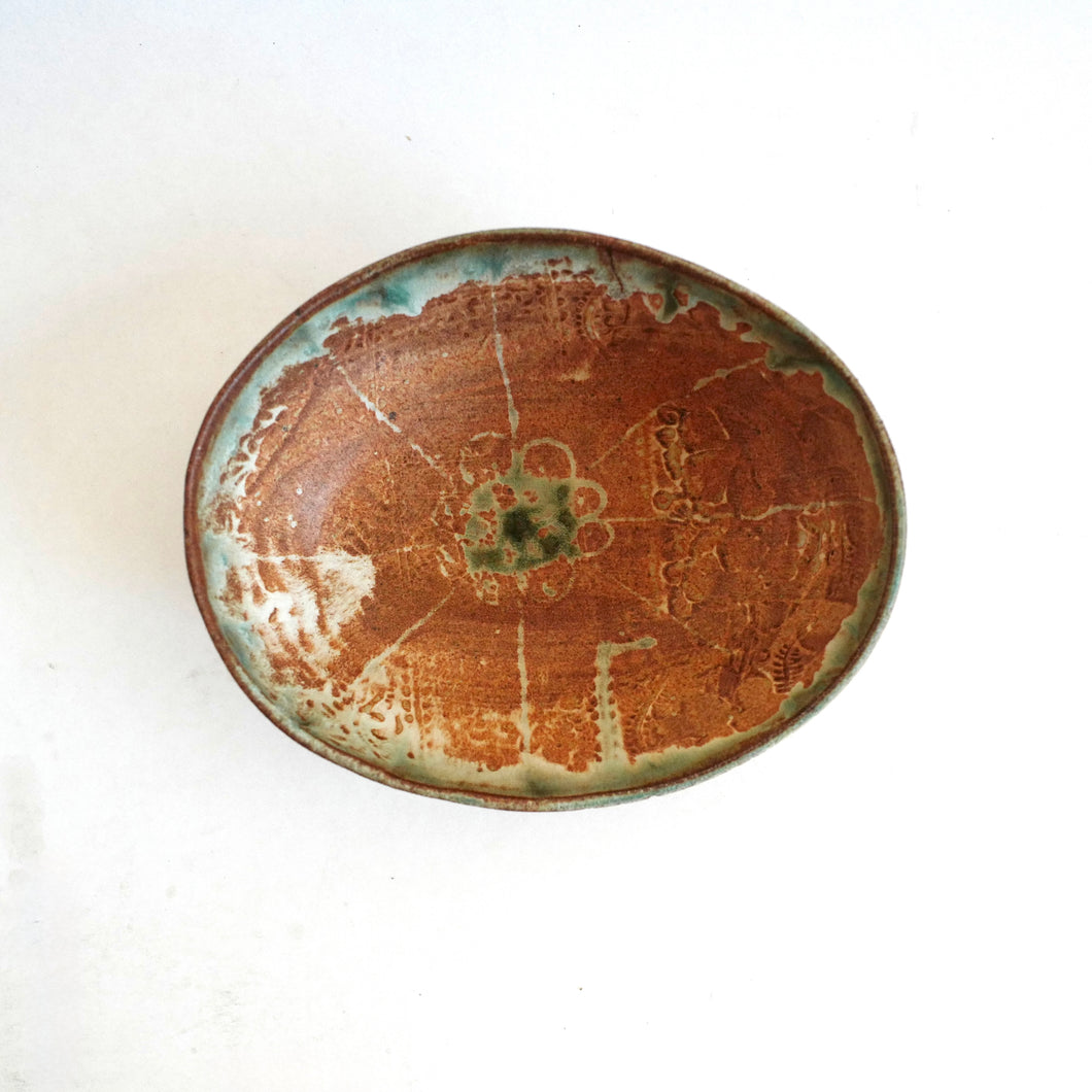 Ceramic plate with brown and green glaze on a white background