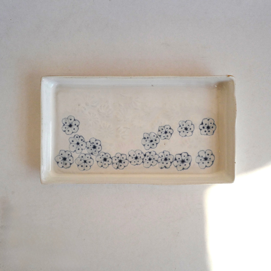 Rectangular ceramic dish with floral patterns on a plain background
