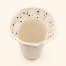 White ceramic vase with flower pattern on a white background