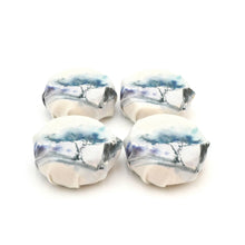 Four individually wrapped soaps on a white background