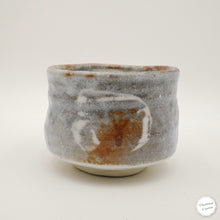 A handmade ceramic matcha tea bowl with a textured, hand-painted glaze in gray, white, and earthy brown tones, photographed on a clean white background.