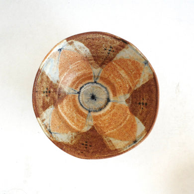 Ceramic plate with a decorative brown and beige pattern on a white background