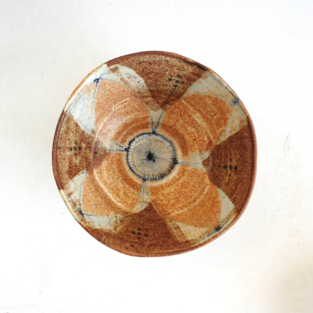 Ceramic plate with a decorative brown and beige pattern on a white background