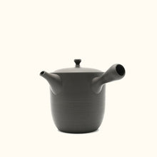 Black teapot with ribbed design on a white background