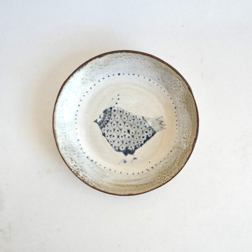 Ceramic plate with textured surface and bird pattern on a white background