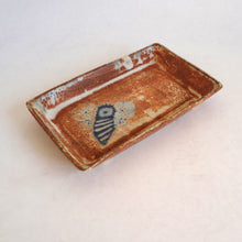 Rectangular ceramic dish with decorative elements on a light background