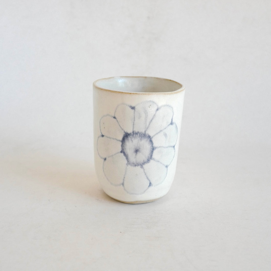 White Tumbler with blue flower pattern on beige background