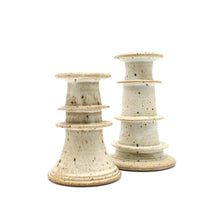 Two ceramic candle holders with a textured surface on a white background