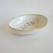 White ceramic bowl with decorative elements on a light gray background
