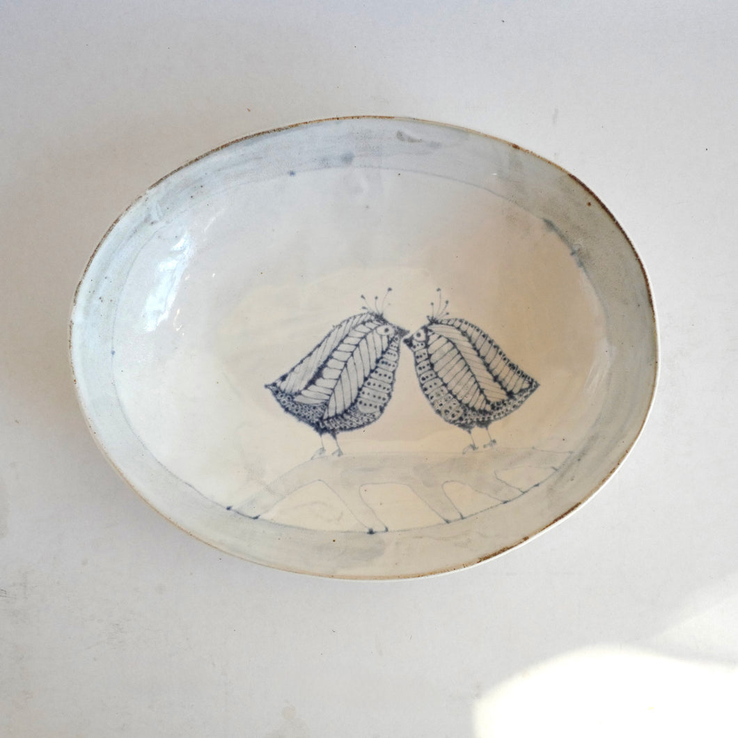 Ceramic plate with blue line art of love birds on a white background