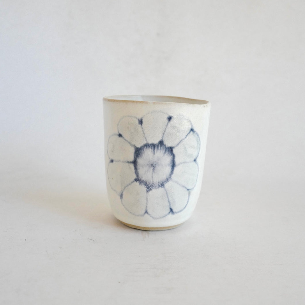White Tumbler with blue flower pattern on beige background