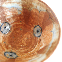 Close-up of a ceramic bowl with brown glaze and blue drawing on a white background