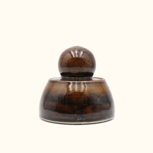 Brown ceramic object with a spherical top on a white background