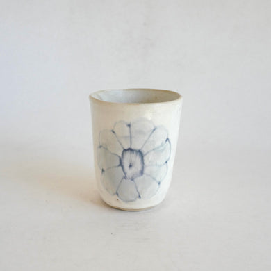 White Tumbler with blue flower pattern on beige background